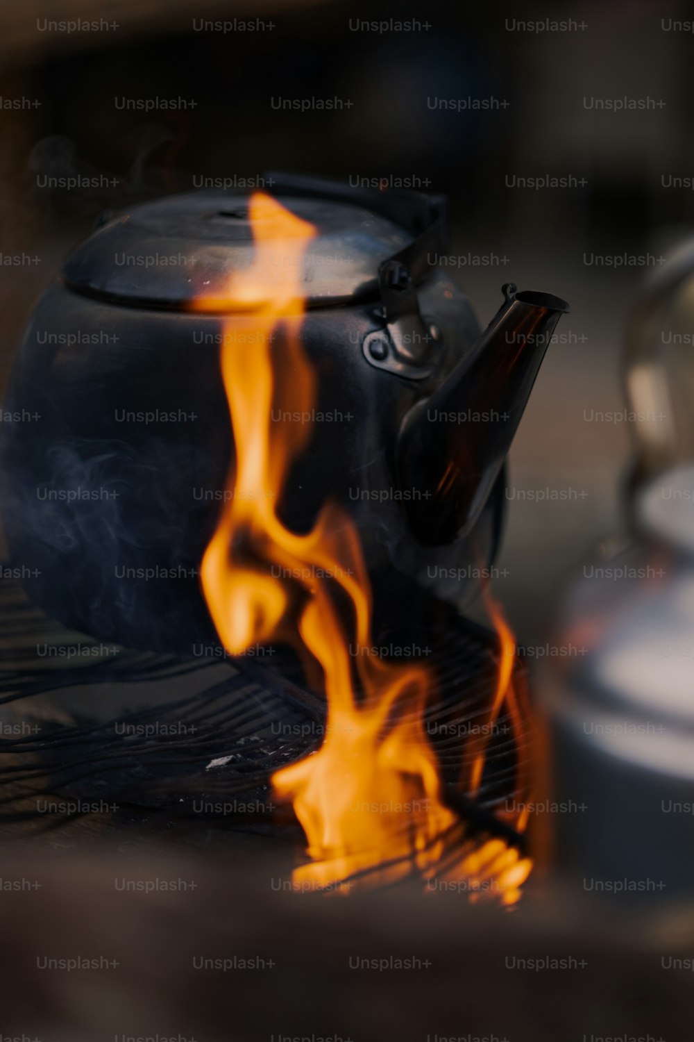 una teiera su una griglia con fiamme che escono da essa