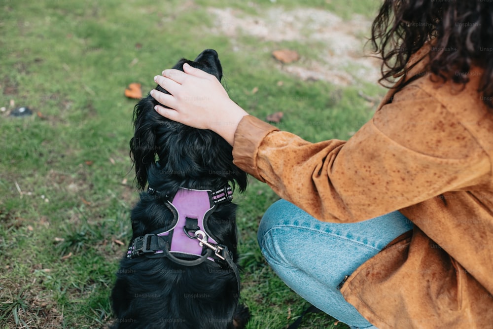 a woman petting a black dog in a field