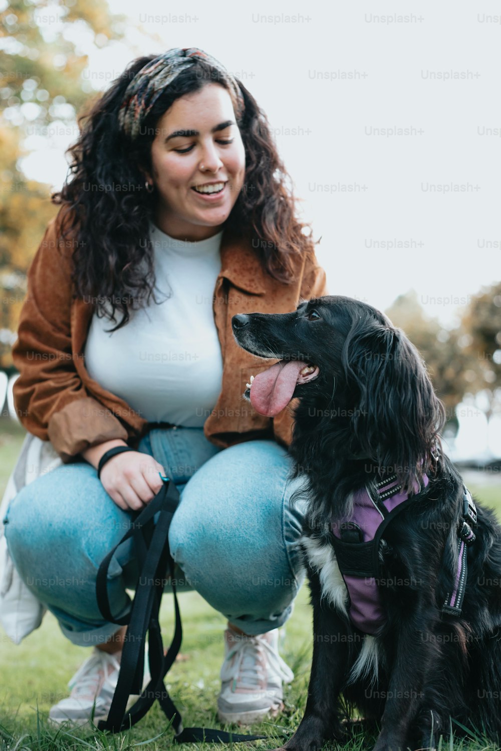 Una donna inginocchiata accanto a un cane nero