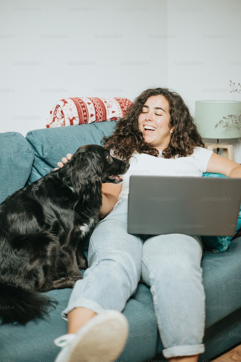a woman sitting on a couch with a dog and a laptop