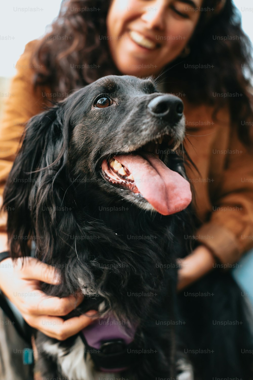 a woman smiles as she holds a black dog