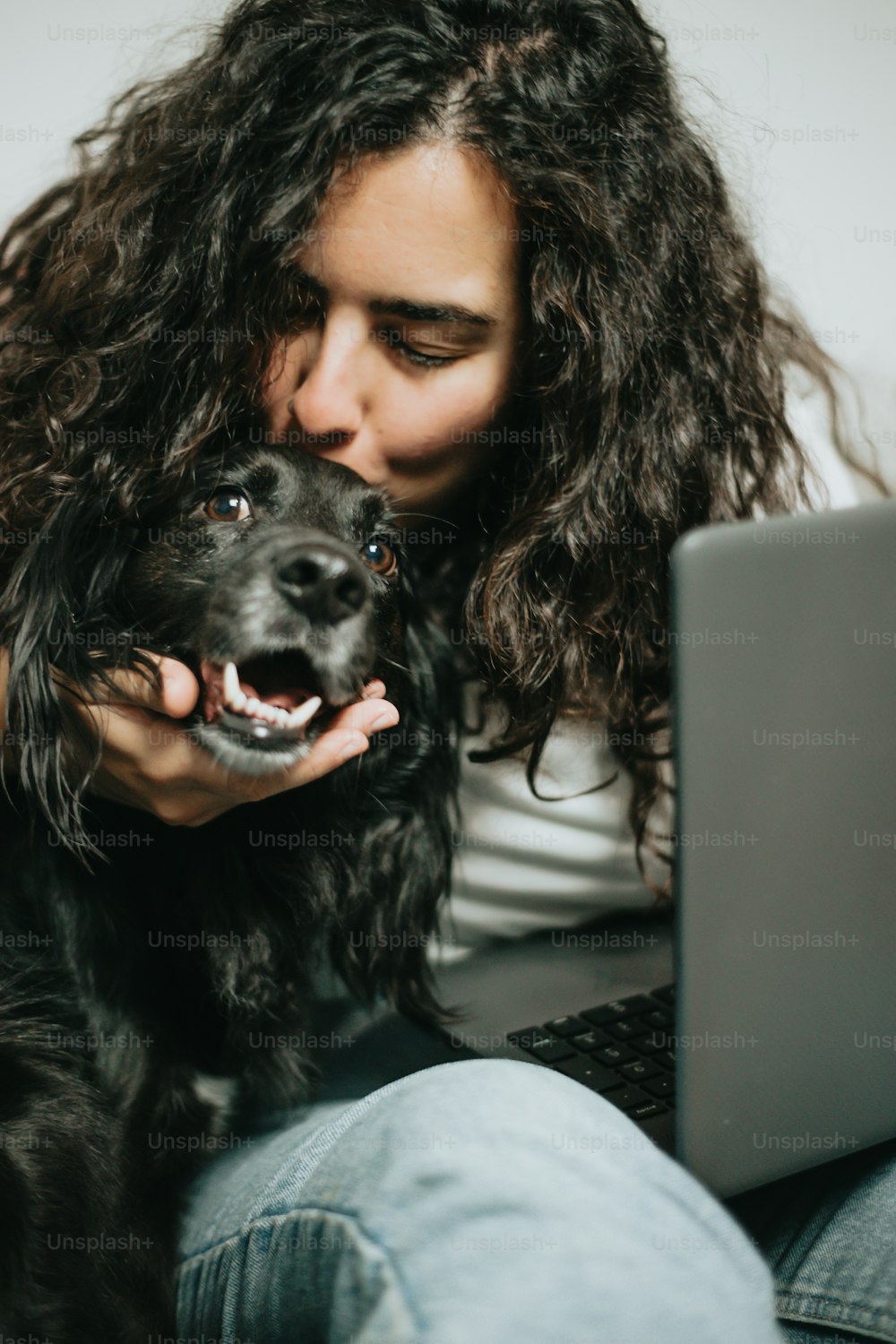 a woman sitting on a couch with a laptop and a dog