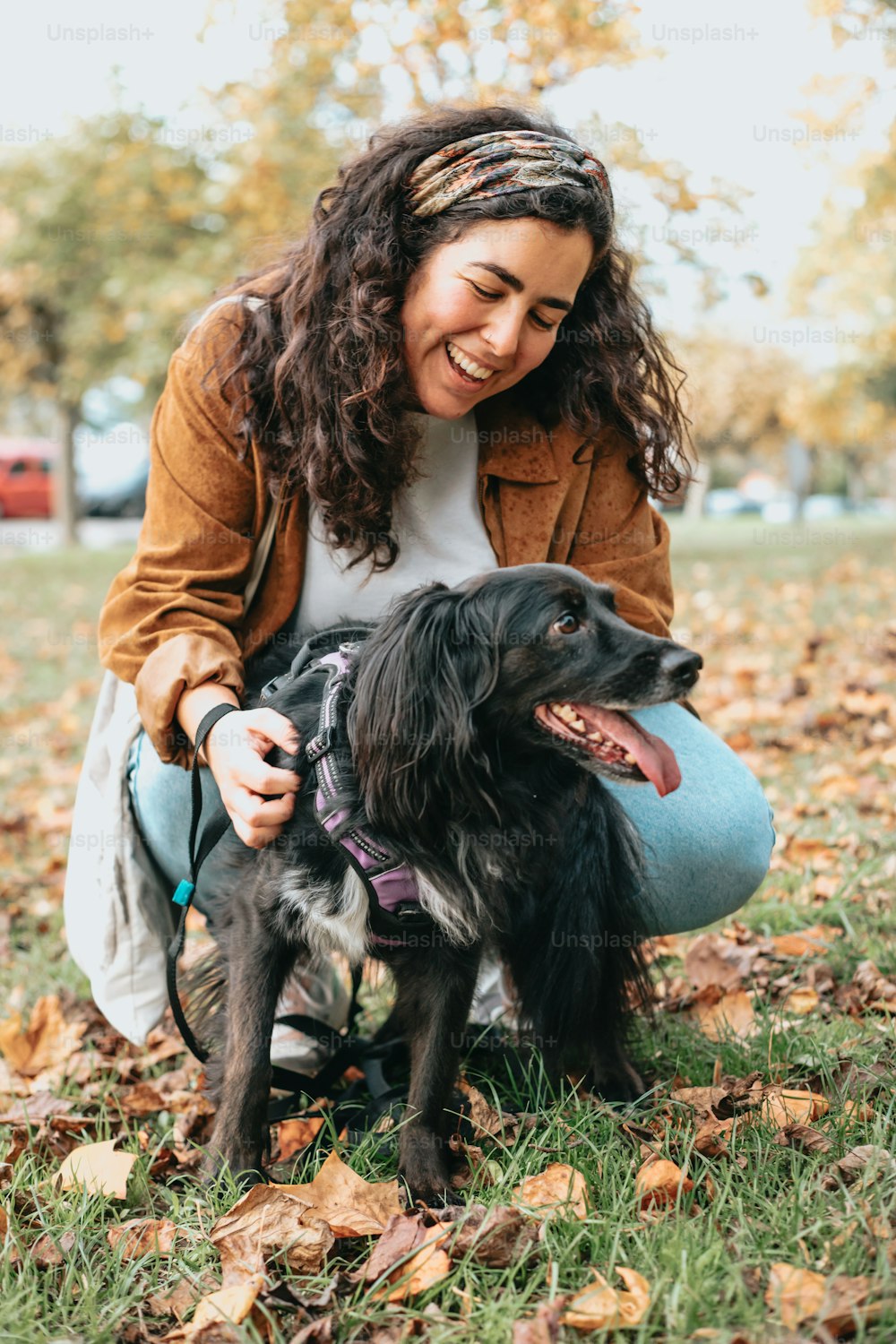 a woman petting a black dog in a park