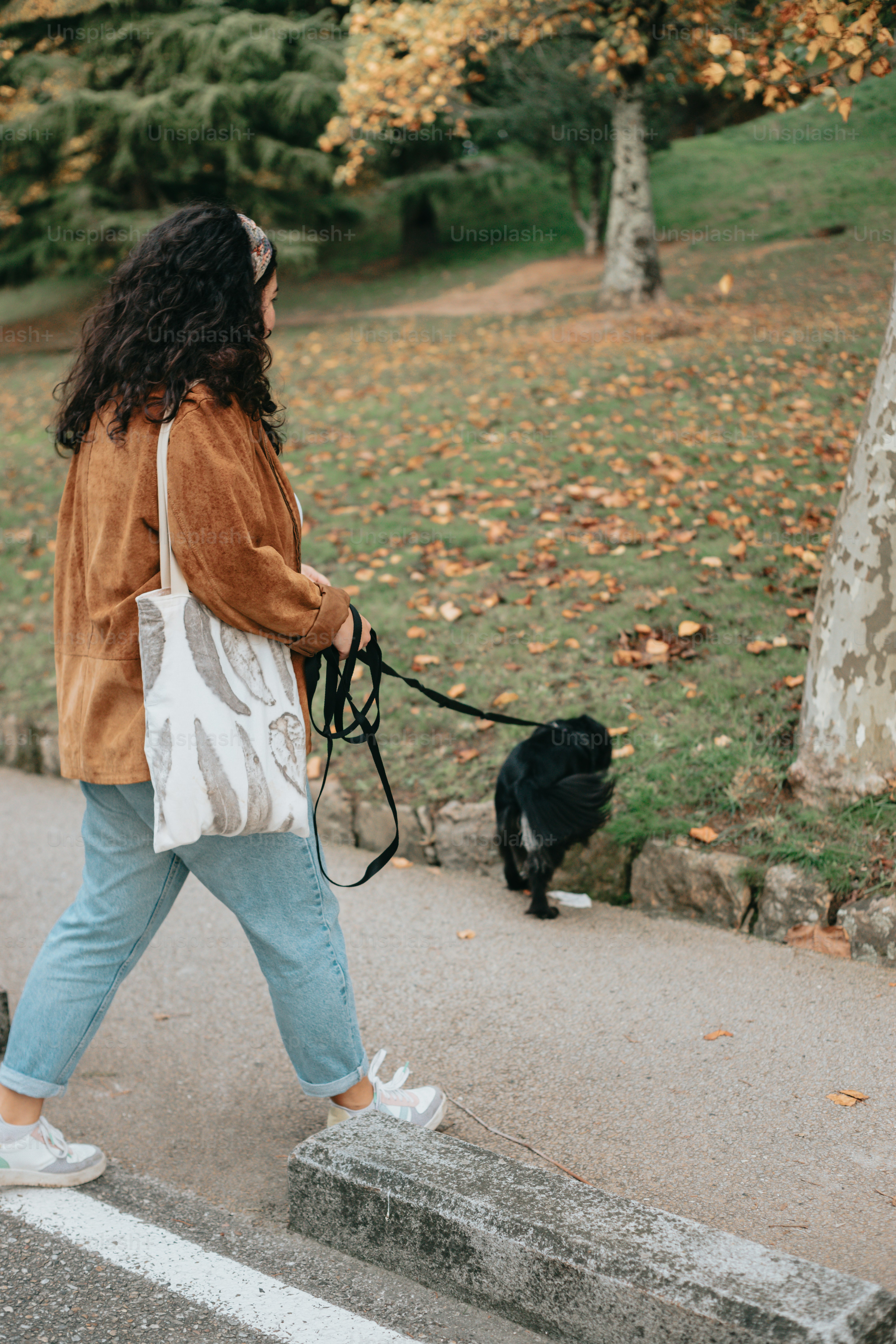 a woman walking a dog down a sidewalk