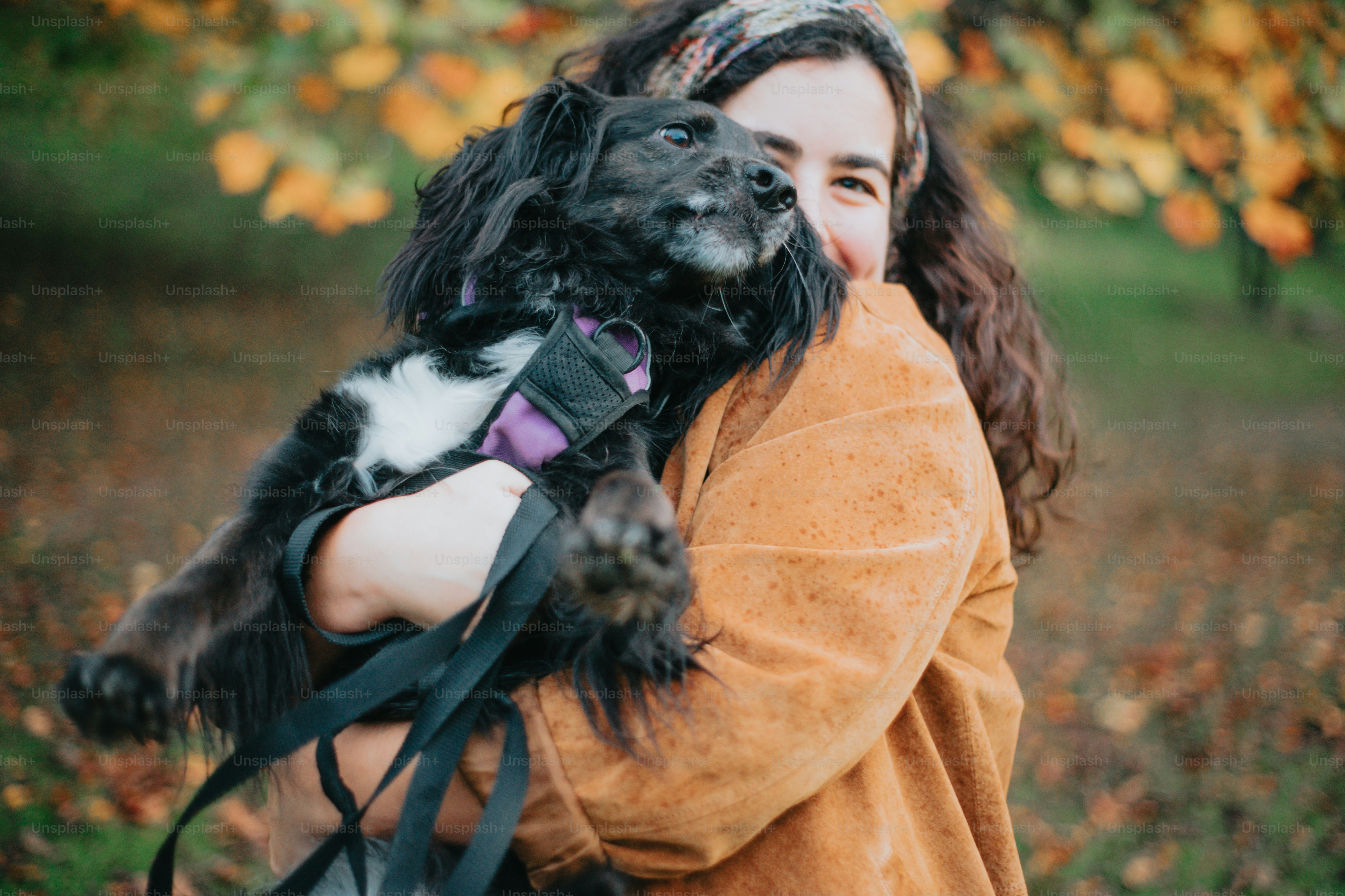 a woman holding a black and white dog in her arms