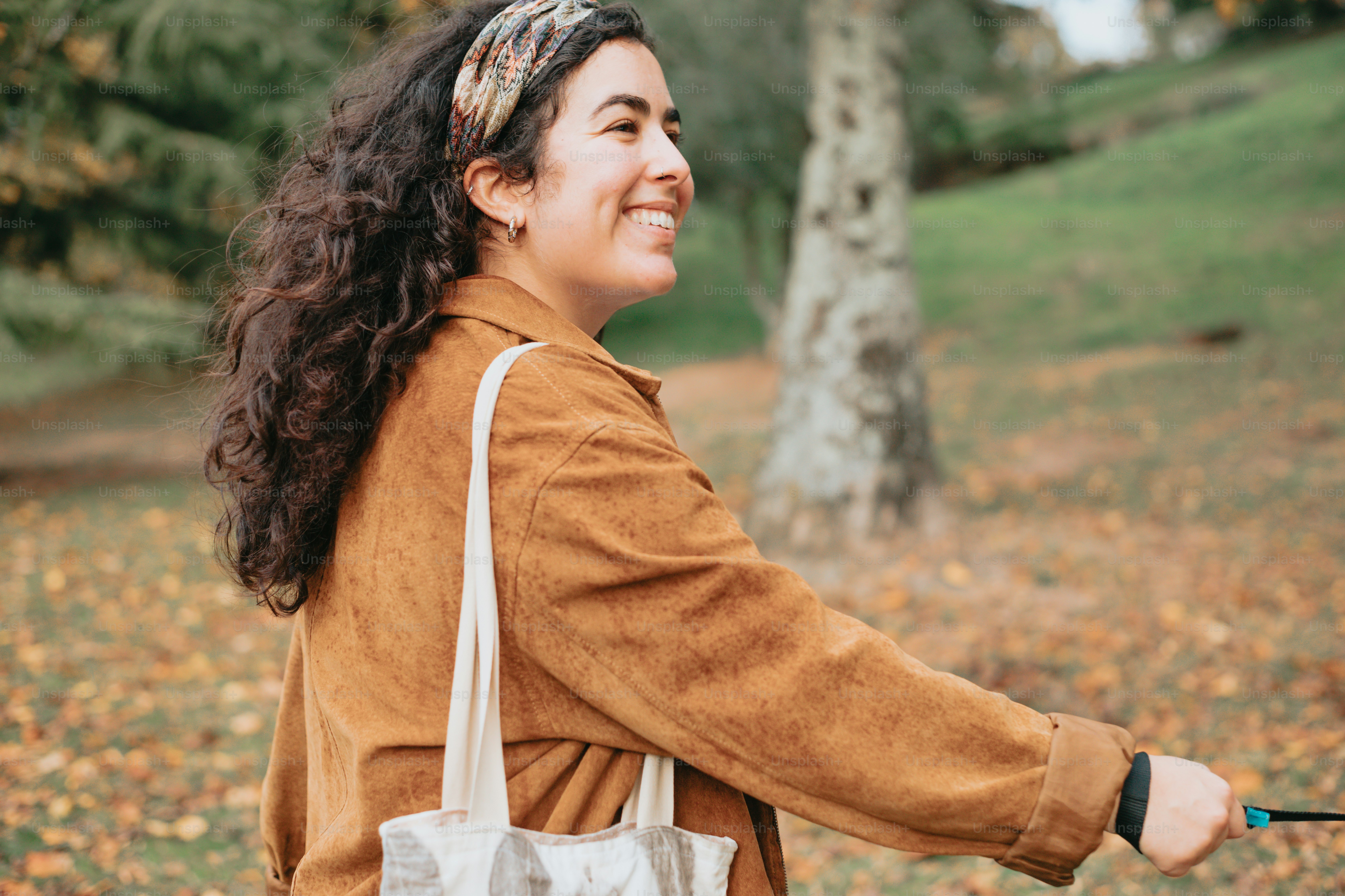 a woman smiles as she walks through a park