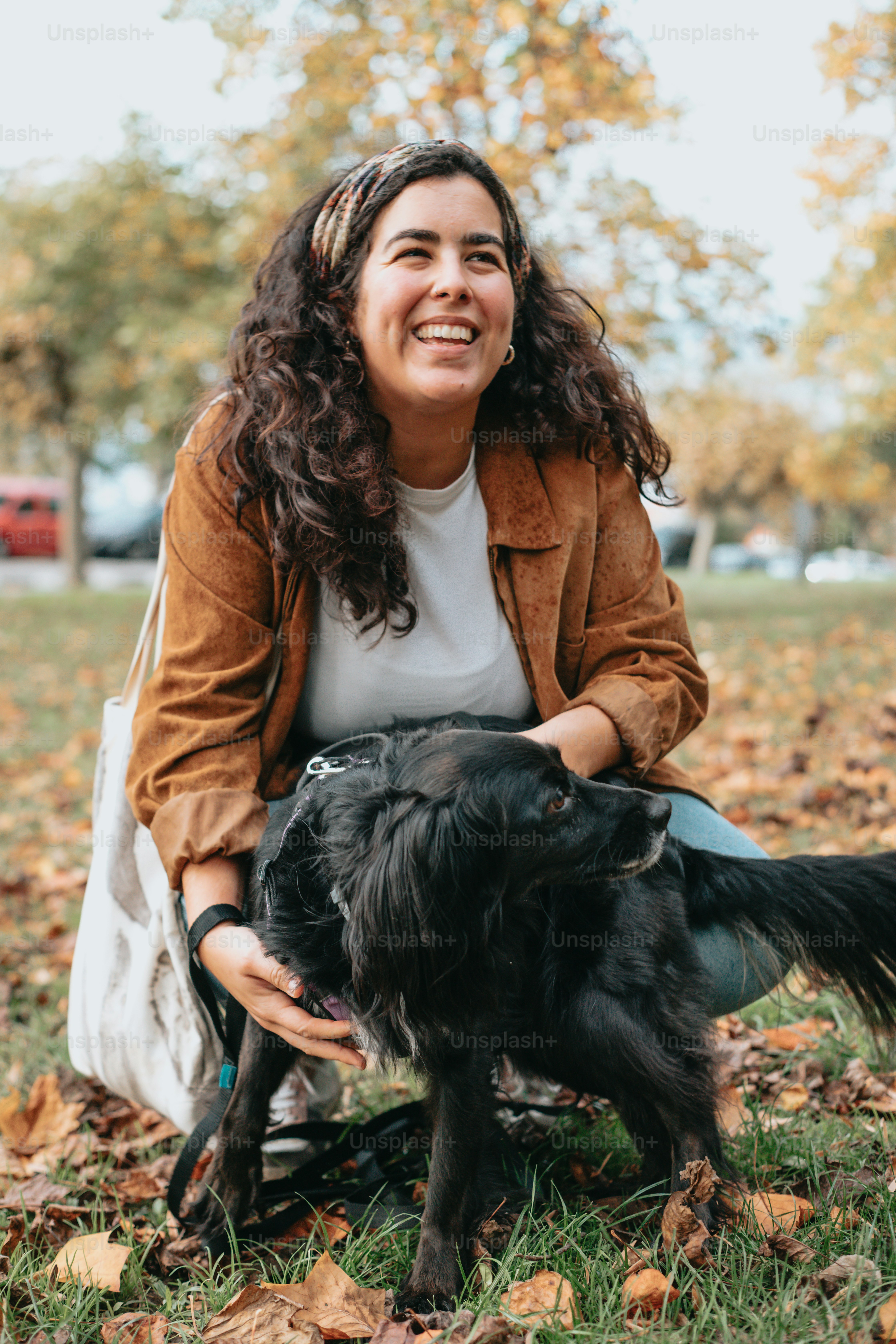 A woman kneeling down next to a black dog photo – Happy day Image on ...