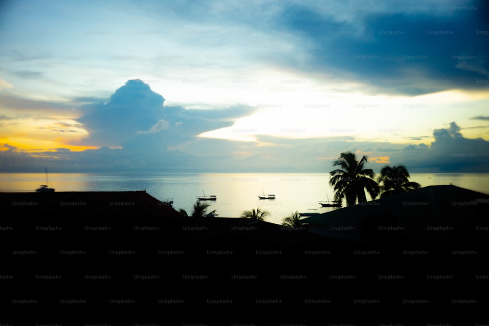 the sun is setting over the ocean with boats in the water