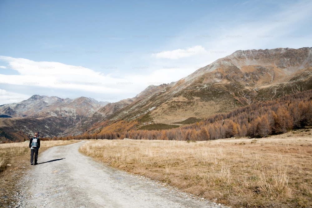 a person standing on a dirt road in the mountains