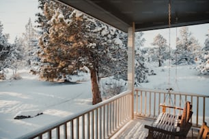 a porch with a swing and snow covered trees