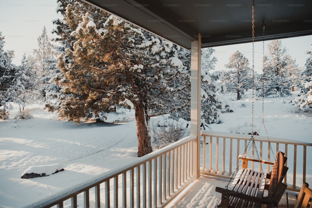 a porch with a swing and snow covered trees