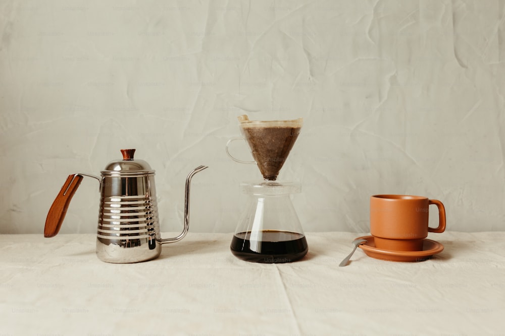 un tavolo sormontato da una caffettiera accanto a una tazza di caffè