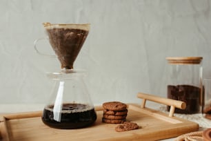 a wooden tray topped with cookies and a coffee pot