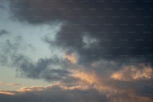 um avião voando através de um céu nublado ao pôr do sol