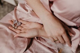 Eine Frau in einem rosafarbenen Kleid, die zwei Ringe hält
