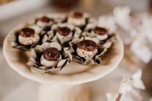 a cake plate topped with cupcakes covered in chocolate frosting