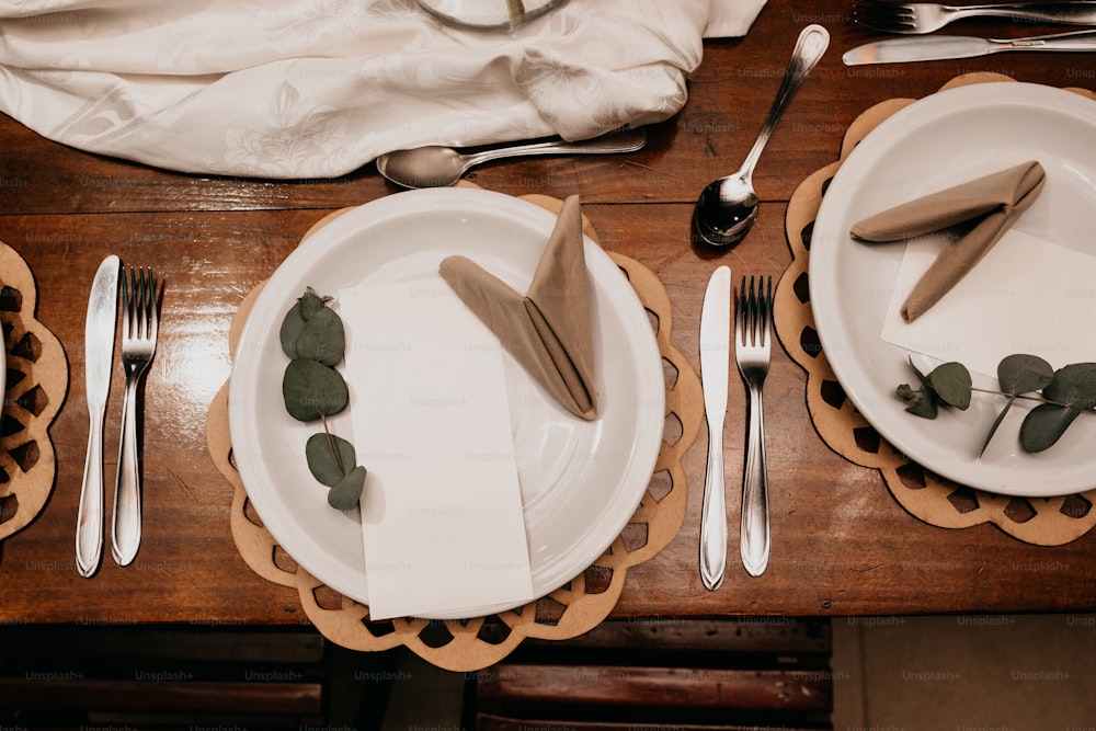 uma mesa de madeira coberta com pratos brancos e talheres