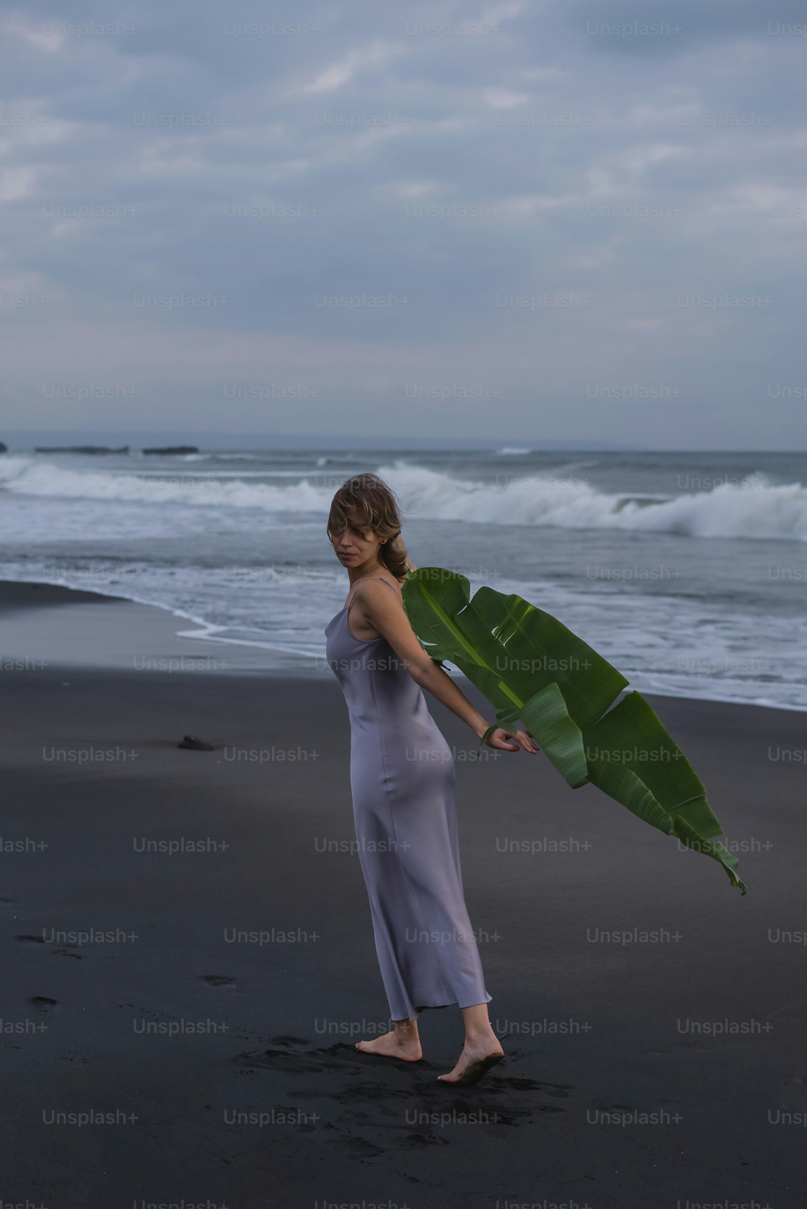 Una donna che tiene una grande foglia di banana su una spiaggia