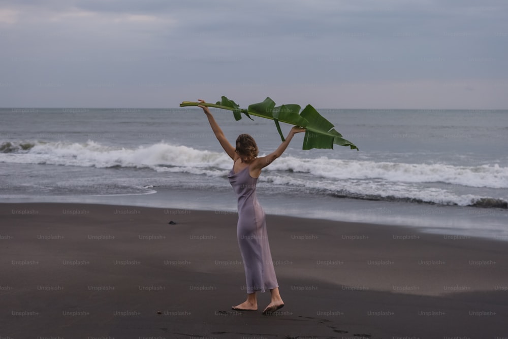 uma mulher em pé em uma praia segurando um pedaço de papel