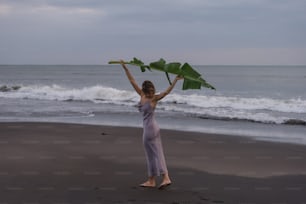 a woman standing on a beach holding up a piece of paper