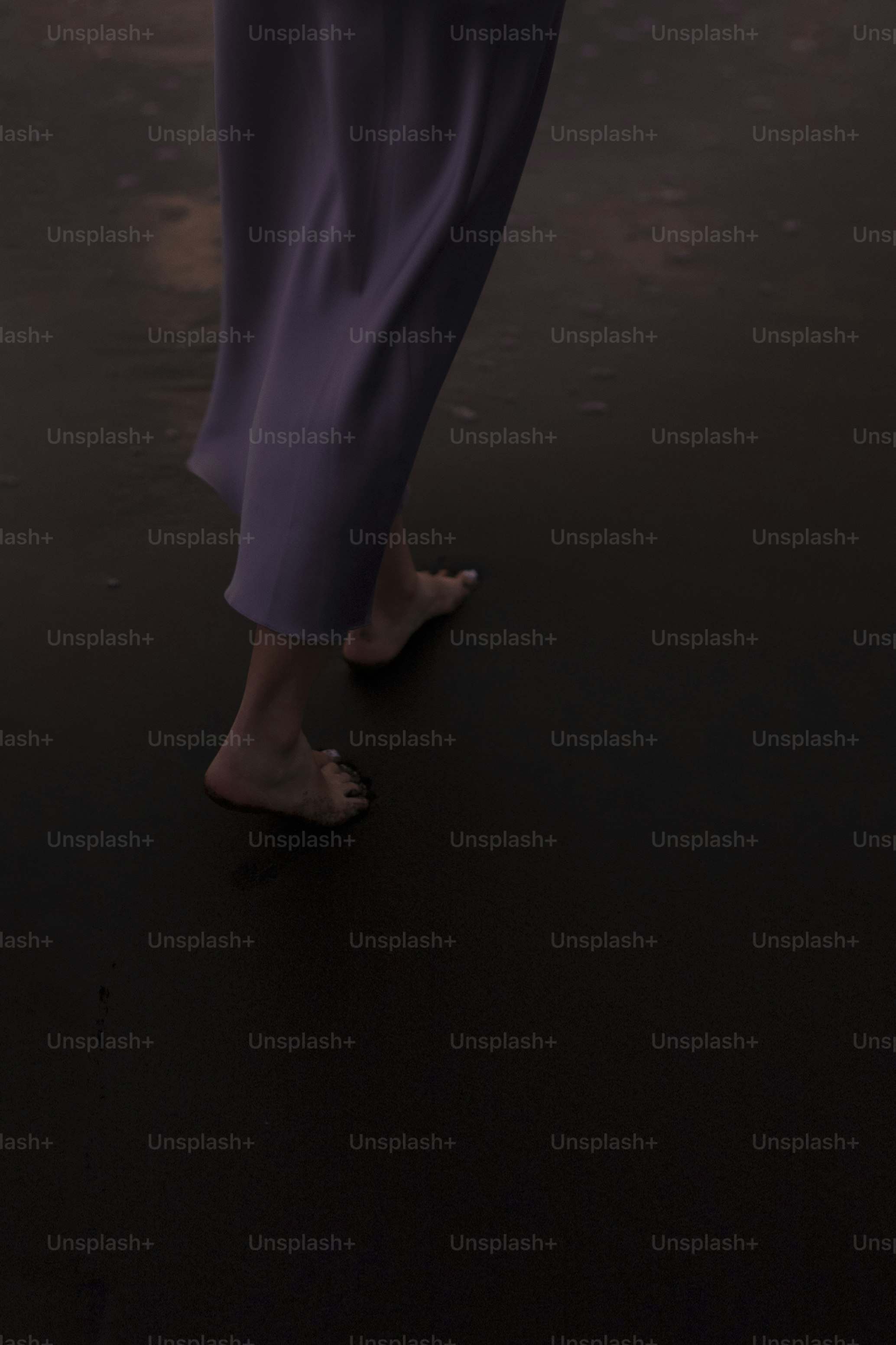 a woman in a purple dress walking on a beach