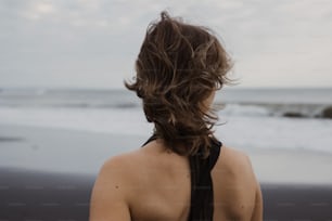 a woman standing on a beach looking at the ocean