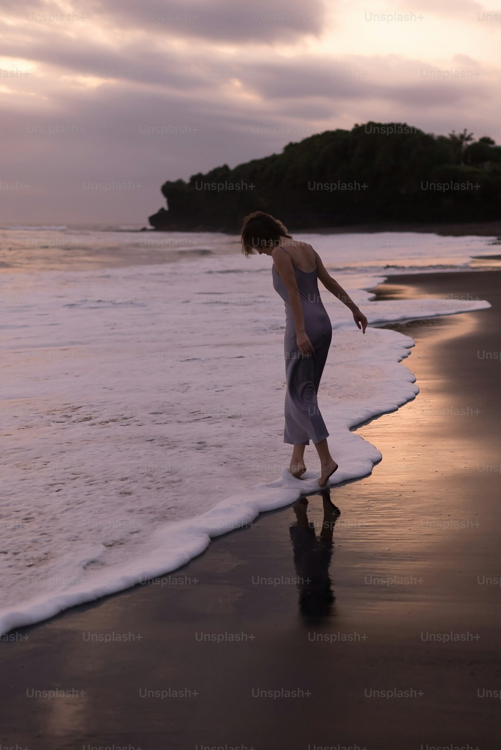 Eine Frau, die an einem Strand am Meer entlang geht