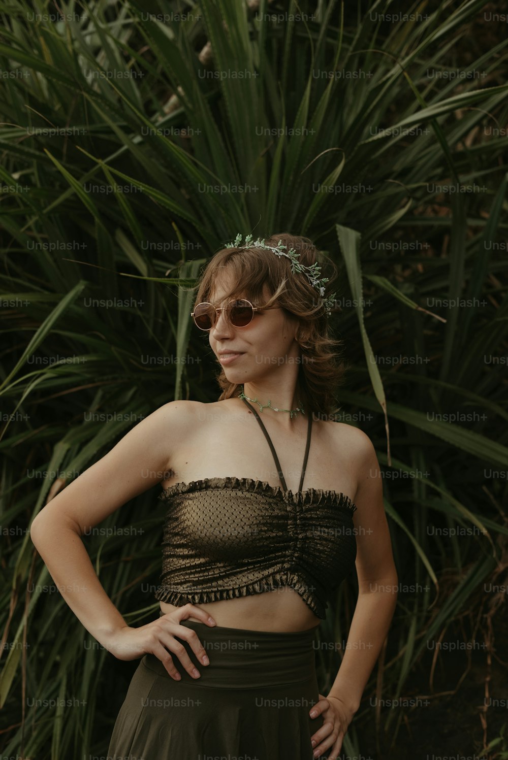 a woman standing in front of a bush wearing sunglasses