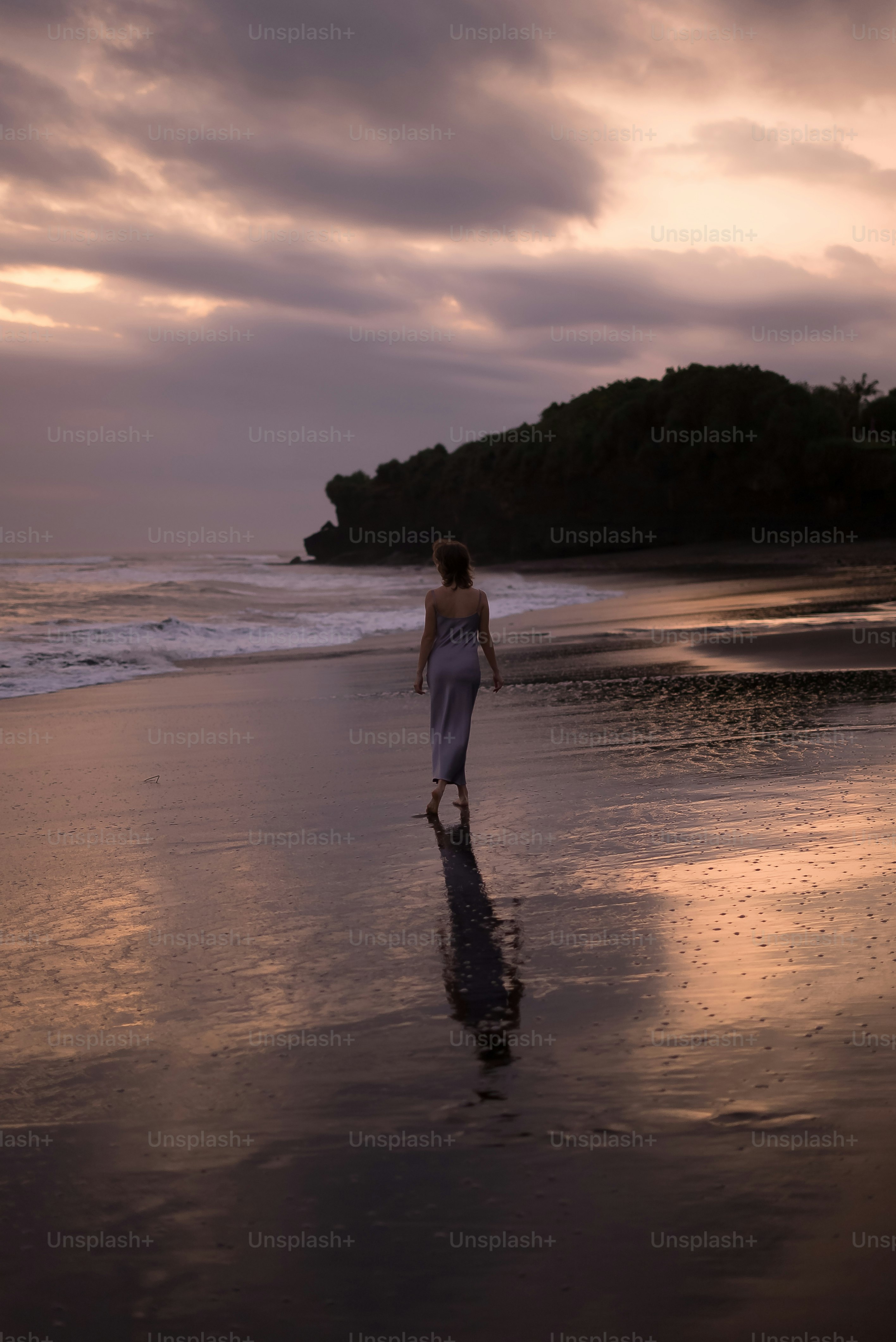 uma mulher caminhando ao longo de uma praia ao lado do oceano