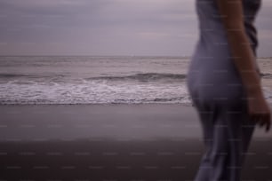 Une femme debout au sommet d’une plage au bord de l’océan
