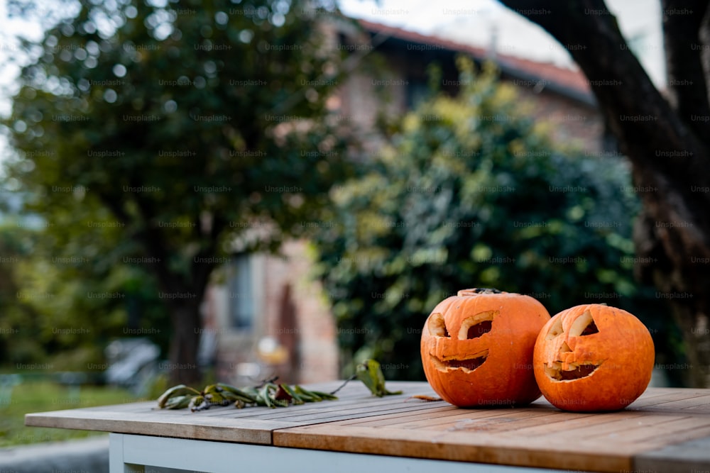 two carved pumpkins sitting on top of a wooden table