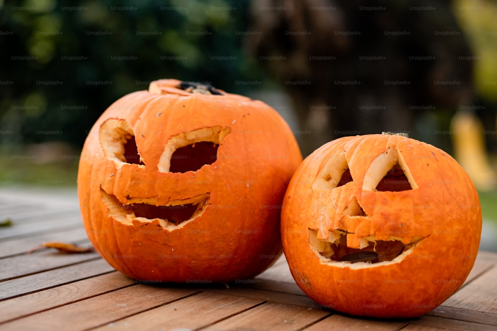 two carved pumpkins sitting on top of a wooden table