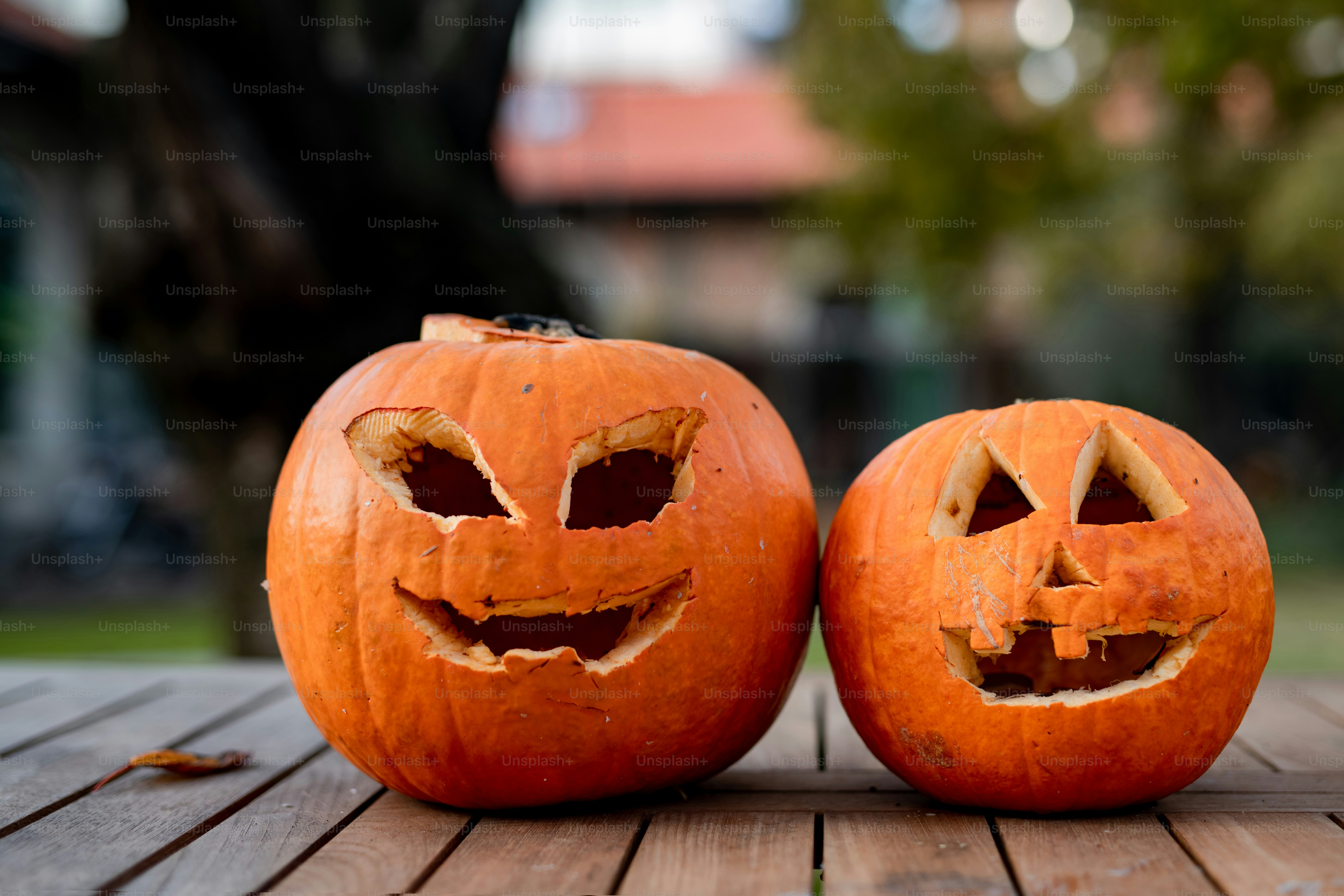 two carved pumpkins sitting on top of a wooden table
