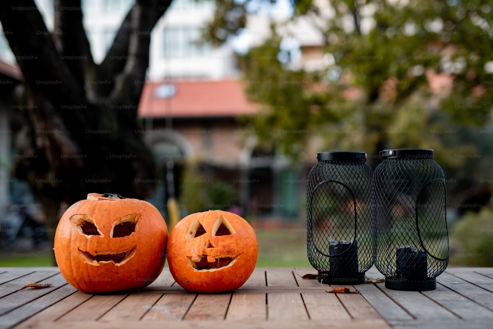 two carved pumpkins sitting on a wooden table