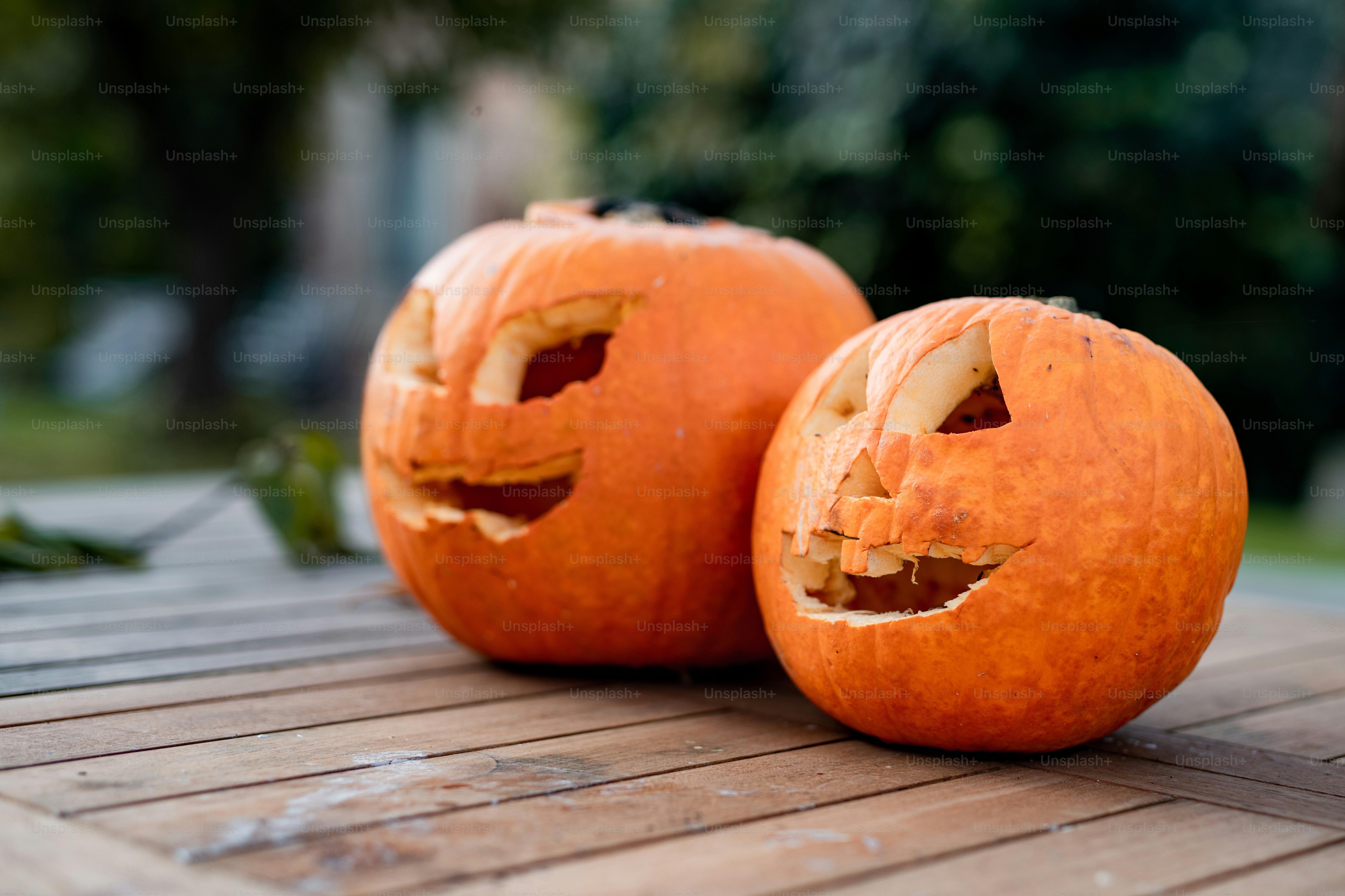 two carved pumpkins sitting on top of a wooden table