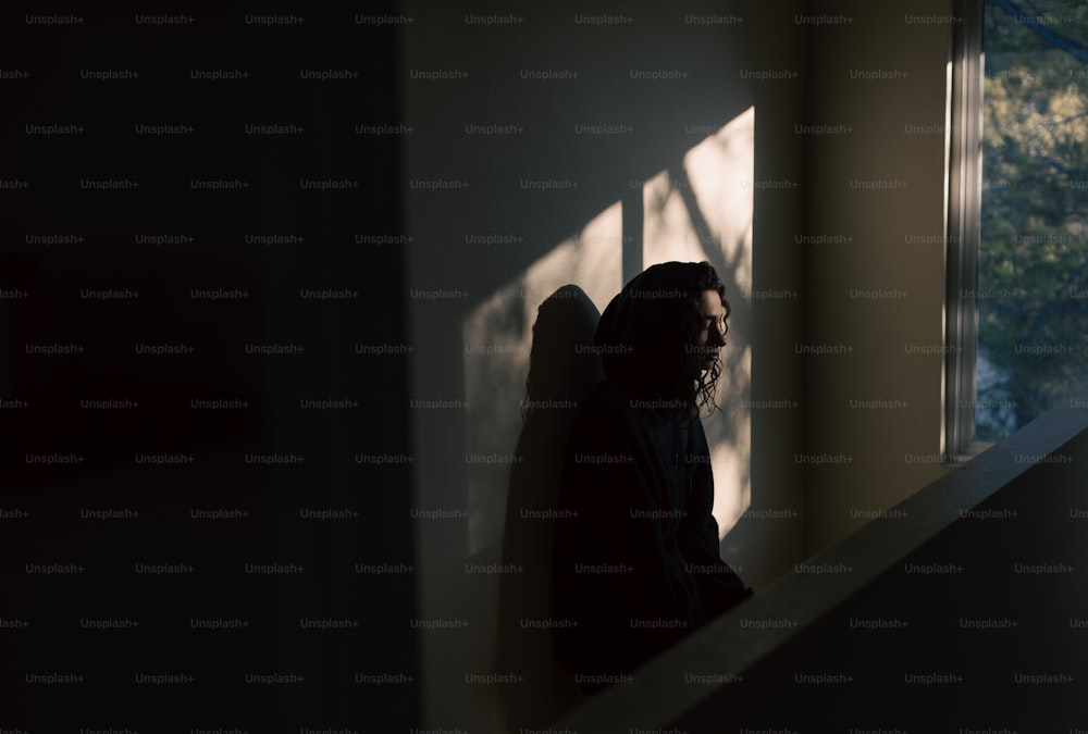 Eine Frau, die vor einem Fenster in einem dunklen Raum steht
