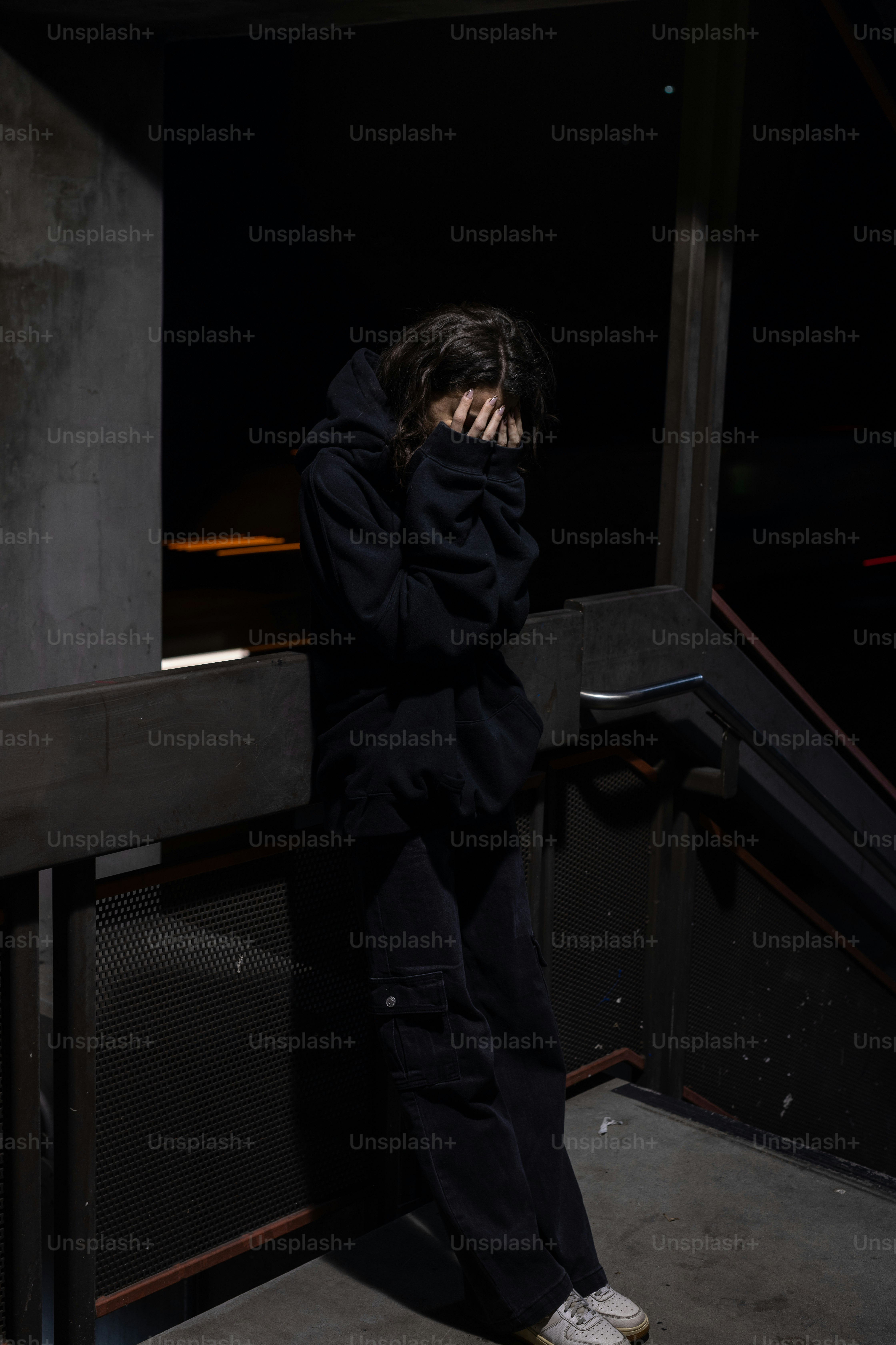 a man standing in a dark room with his hands on his face