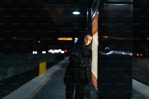 a woman leaning against a wall in a train station