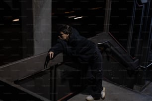 Un homme en veste noire appuyé contre une balustrade