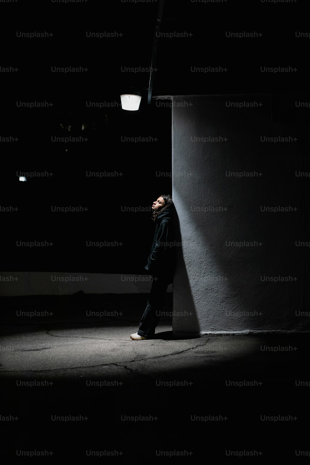 a man standing against a wall in the dark