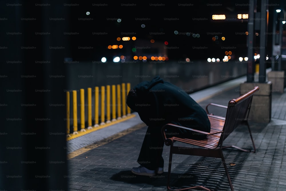 una persona seduta su una panchina al buio