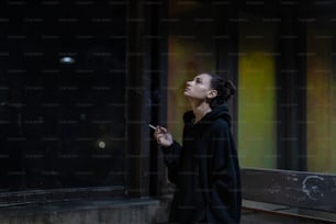 Eine Frau, die auf einer Straße in der Stadt eine Zigarette raucht