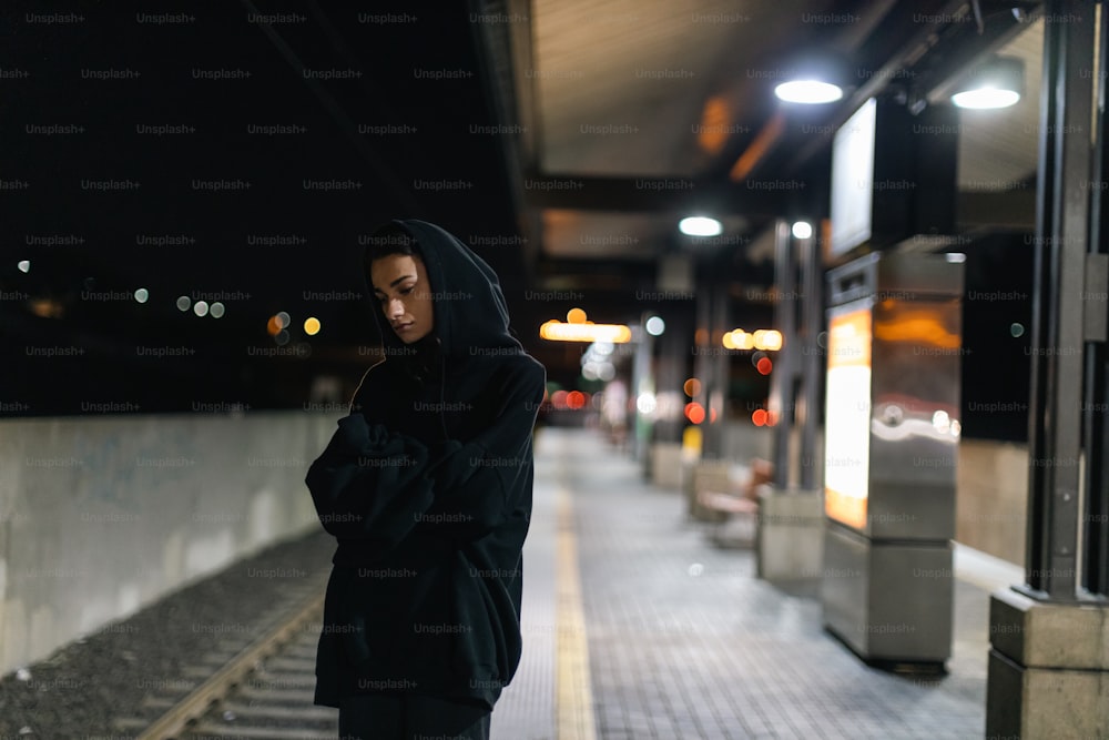 a person standing on a sidewalk at night