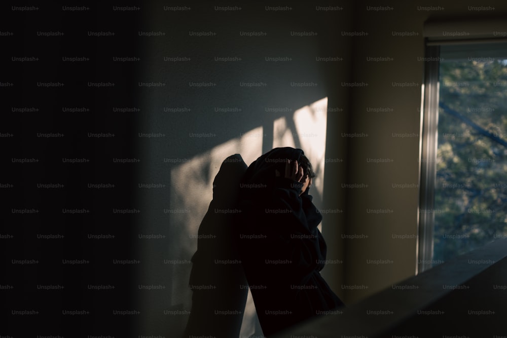 une personne debout dans une pièce sombre, dos à la caméra