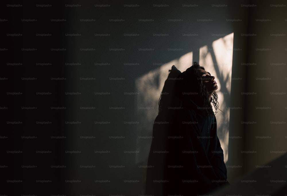 uma pessoa em pé em um quarto escuro com a cabeça baixa