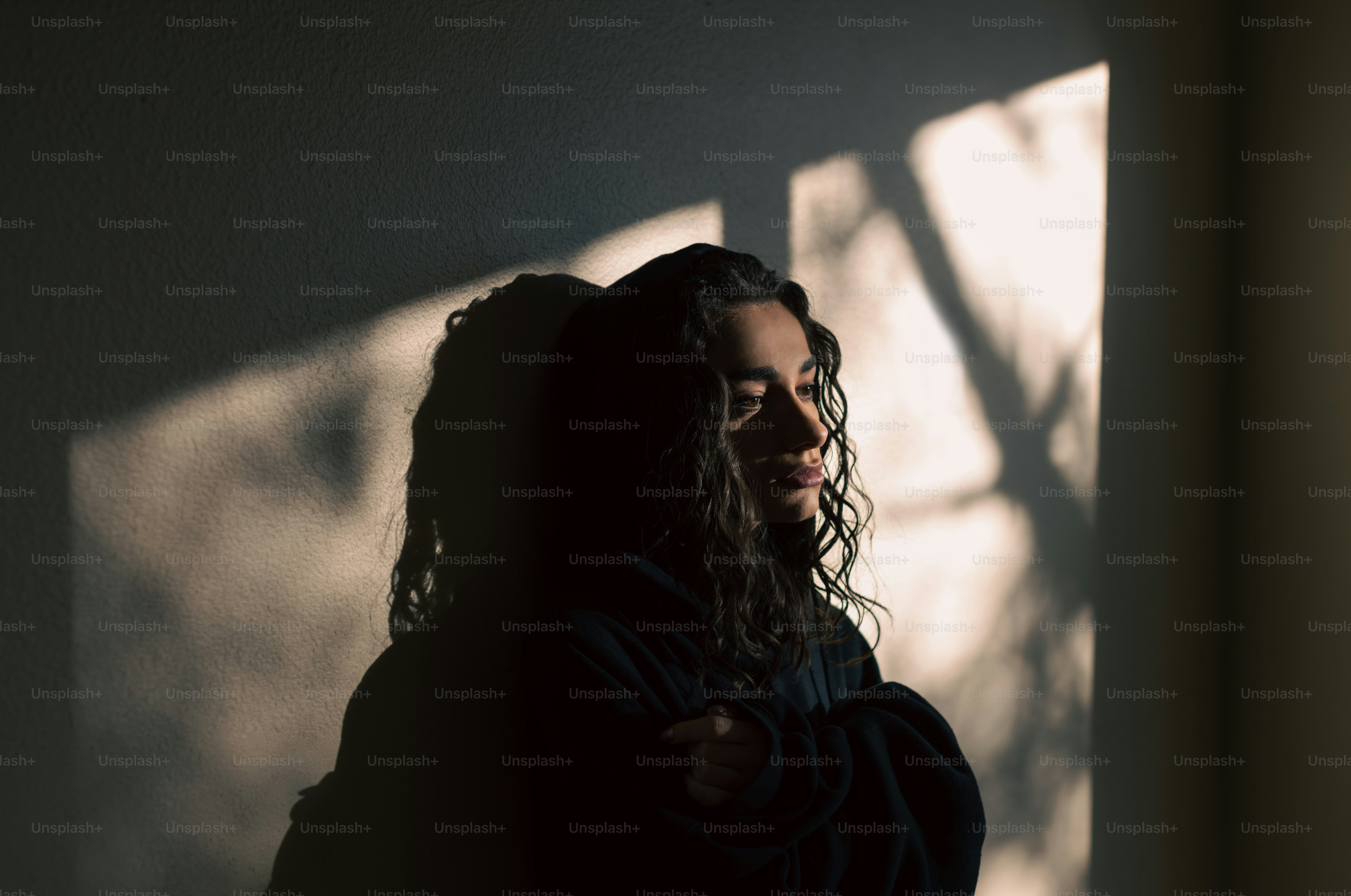 a woman standing in the shadows of a wall