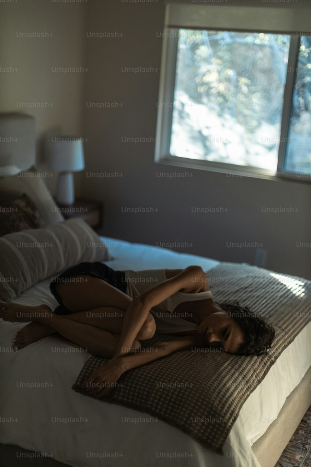 a woman laying on top of a bed next to a window