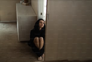 a woman sitting on the floor in a doorway