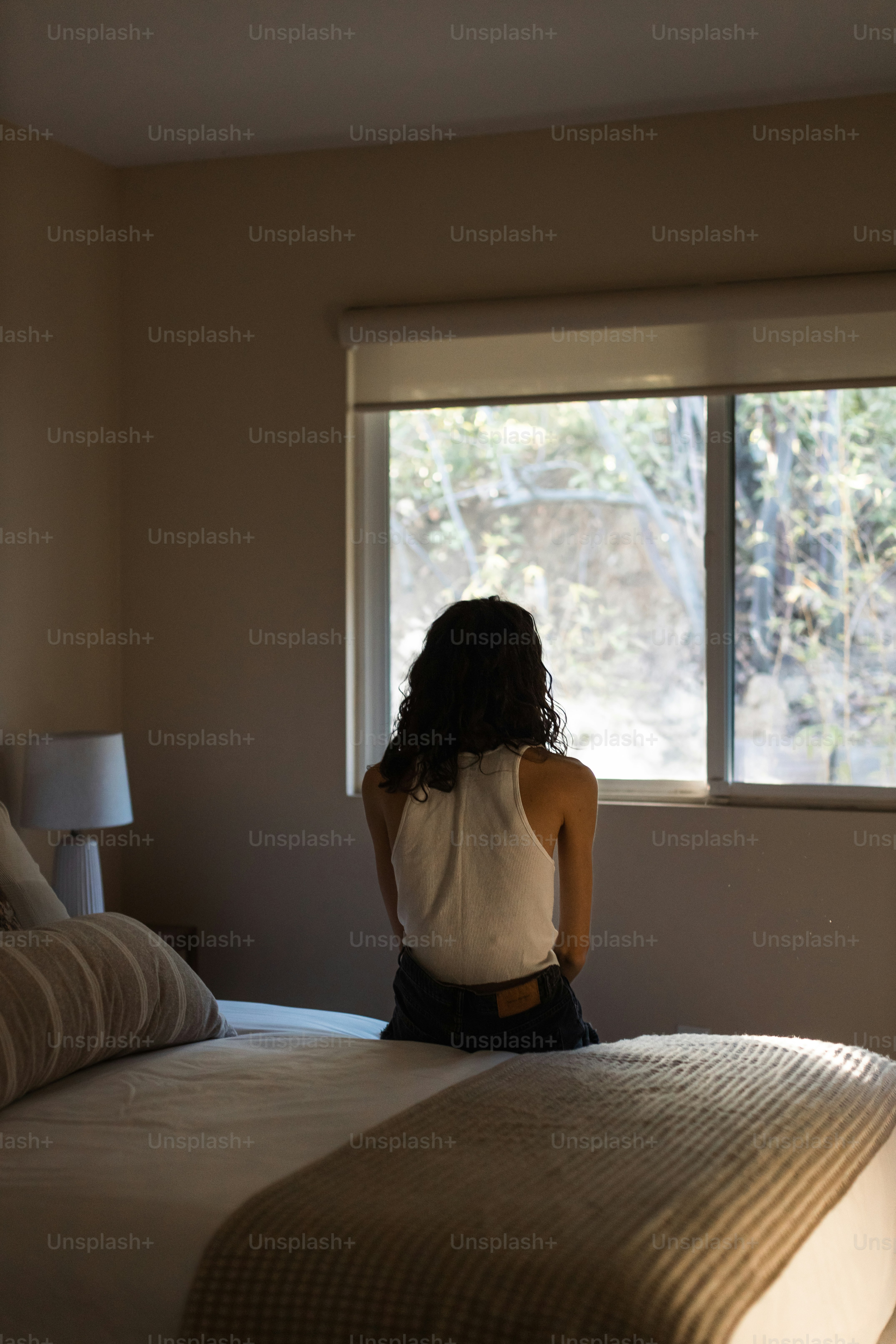 a woman sitting on a bed looking out a window
