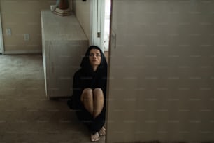 una donna seduta sul pavimento in una stanza